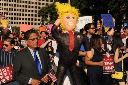 Protestors march through downtown toward the American Airlines Center with Donald Trump pinatas. Photo Credit: Ryan Miller