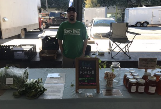 John Michael Barns of HalleluYah Farms stands with his honey and produce at the farmers market.png