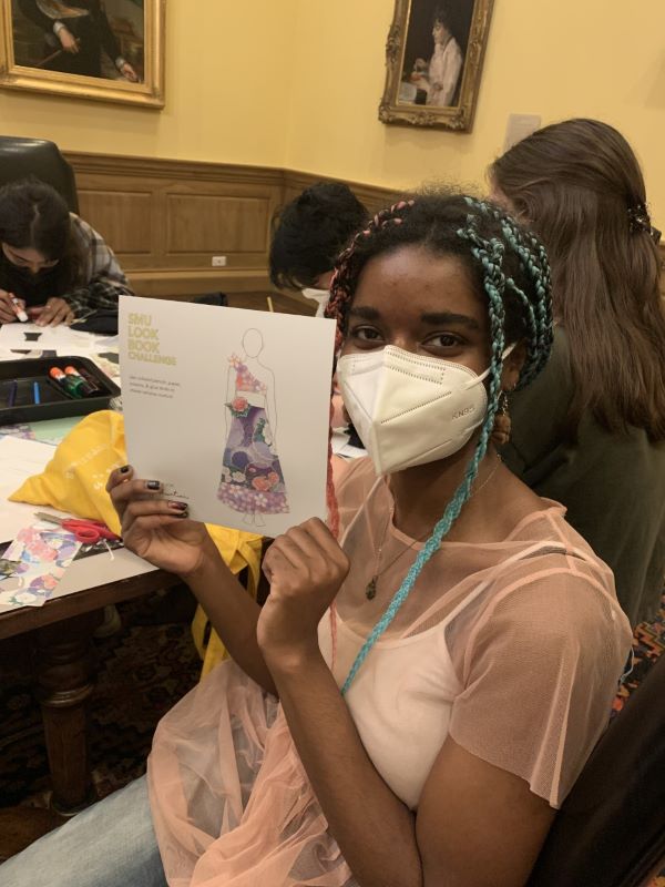 Girl holds up a paper dress she designed for the SMU lookbook challenge.