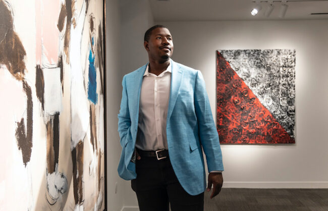 Kelvin Beachum stands in front of some pieces of his family's art collection, “Narrative as Reality: A World Reimagined,” which are featured in an exhibit at SMU’s Hamon Arts Library through May 22. Image Credit: Kim Leeson Photography for SMU