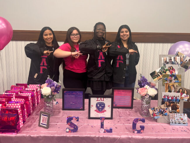 Members of Sigma Lambda Gamma, the first sorority at SMU to explicitly accept non-binary persons, pose with their sorority's hand sign in front of their booth at the Multicultural Greek Open House.