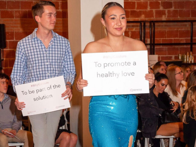 Models walk the runway at Alpha Chi Couture holding signs representing why they chose to walk in the show to support domestic violence survivors. Image courtesy of SMU Alpha Chi Omega's Instagram.